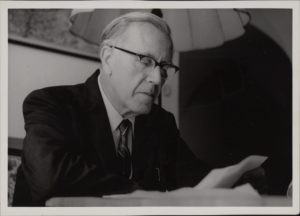 Dietrich von Hildebrand sitting in office reading a paper